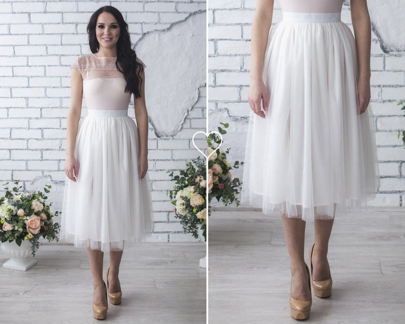 Fluffy tutu ivory tulle skirt. Midi length, waist fit. Has a sewn-in waistband about two inches wide. Sewn from several layers of soft tulle, lined with chiffon. Very flowy and airy.
