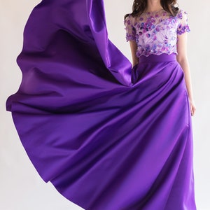 Long satin full sun purple skirt. Fitted at the waist, a sewn-in wide belt (about 2" wide) closes with a hidden zipper. Made of dense satin with a beautiful matte sheen. Has pockets in the side seams. Without lining.