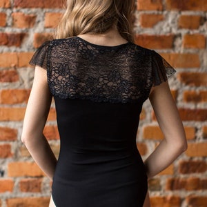 May include: Black bodysuit with a lace overlay on the back. The bodysuit has a scoop neck and short sleeves.