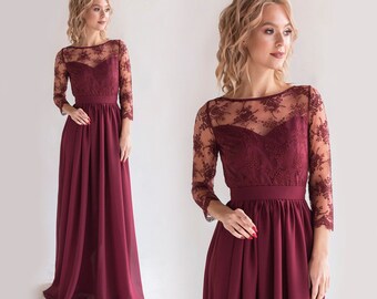 May include: A long, burgundy maxi dress with a lace overlay and long sleeves. The dress has a fitted bodice and a flowing skirt.