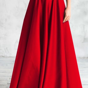 Long satin full sun red skirt. Fitted at the waist, a sewn-in wide belt (about 2" wide) closes with a hidden zipper. Made of dense satin with a beautiful matte sheen. Has pockets in the side seams. Without lining.