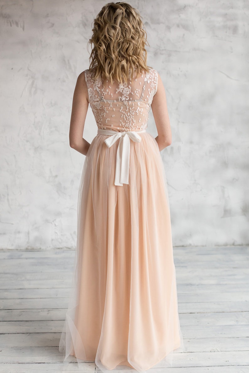 Puede incluir: Un vestido maxi de tul color melocot&oacute;n con un corpi&ntilde;o de encaje blanco y una faja de sat&eacute;n blanco atada en un lazo en la espalda.
