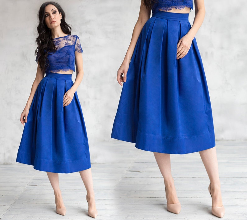 Stylish midi blue skirt with a wide pleats. Waist fit, has a sewn-in waistband about two inches wide. Made of polished cotton, with a slight sheen. Pockets in the side seams. Wide cuff at the bottom to keep skirt's shape. Hidden zip at the back.