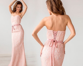 May include: A pink strapless lace dress with a fitted bodice and a flowing skirt. The dress has a satin ribbon tied at the waist and a lace-up back.