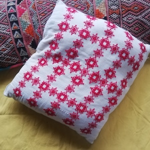 Red cross-stitch embroidered cushion on an ecru background in Scandinavian or Berber style