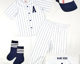 May include: A white and blue striped baseball uniform set for kids, including a jersey with the letter 'A' on the front, pants, socks, and a baseball cap with a red baseball stitched on the front.
