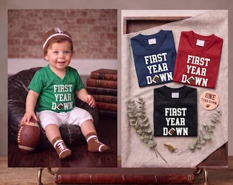 Pode incluir: Uma t-shirt verde com texto branco a dizer FIRST YEAR DOWN e um gráfico de bola de futebol americano, combinada com calções brancos, meias castanhas com tema de futebol e um gorro a condizer. Inclui t-shirts azul-marinho, vermelhas e pretas.