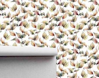 Op de afbeelding: Een witte achtergrond met een herhalend patroon van aquarelbladeren in tinten groen, bruin en roze. De bladeren zijn diagonaal gerangschikt, waardoor een gevoel van beweging ontstaat. De behang is gedeeltelijk uitgerold, waardoor de witte muur erachter zichtbaar wordt.