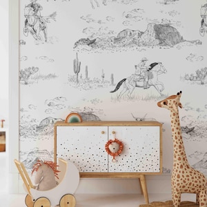 May include: A white wallpaper with a black and white cowboy-themed design. The illustration features cowboys on horseback, cacti, and desert landscapes. A wooden cabinet with a lion decoration and a giraffe toy are in front of the wallpaper.