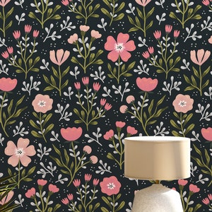 Pu&ograve; includere: Una lampada da tavolo bianca con un paralume beige &egrave; posizionata su un tavolo bianco con uno sfondo nero con un motivo floreale rosa.