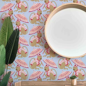 May include: Light blue wallpaper featuring a repeating pattern of cartoon monkeys. Each monkey is dressed in a red and white patterned outfit and holding a matching umbrella. A round wooden mirror and green plants are in the foreground.