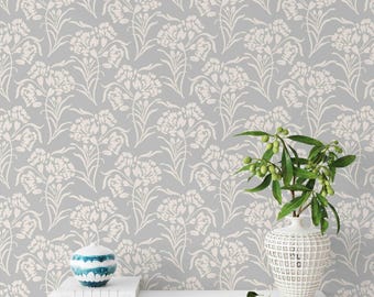 May include: A gray wallpaper with a white floral pattern. A white shelf with a blue and white decorative bowl and a white vase with a green plant is in front of the wallpaper.