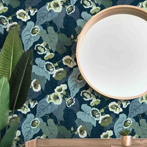 May include: A dark blue wallpaper with a repeating pattern of green leaves and white flowers. The wallpaper is shown on a wall with a round mirror and a small potted plant on a wooden shelf.