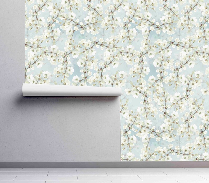 Może przedstawiać: Wz&oacute;r tapety bez szw&oacute;w z białymi kwiatami na delikatnych gałązkach na jasnoniebieskim tle. Kwiatowy wz&oacute;r tworzy delikatną i romantyczną estetykę.