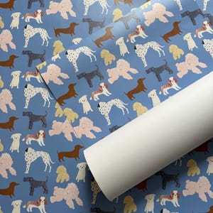 May include: Blue wrapping paper with a repeating pattern of various dog breeds, including a dalmatian, dachshund, poodle, and a cavalier king charles spaniel.