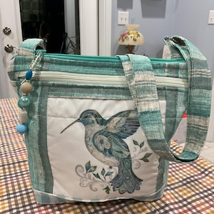 Preciosa cartera de tela con correa para el hombro o cruzada en forma de colibrí con diseño de arte popular en colores pastel 100 % hecha a mano