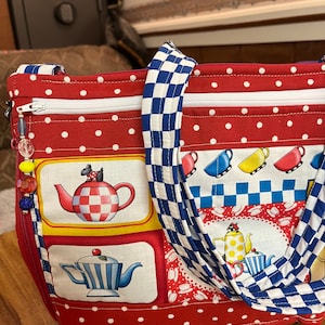 Puede incluir: Bolso de mano de lunares rojos y blancos con correas a cuadros azules y blancos. El bolso presenta un diseño de patchwork con imágenes de teteras y tazas de té.