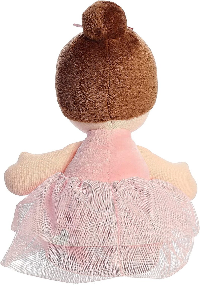 May include: A plush ballerina doll with brown hair in a bun, wearing a pink dress and a tulle skirt.