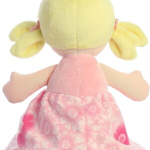 May include: A pink and white plush doll with blonde hair in pigtails. The doll is wearing a pink dress with a floral pattern.