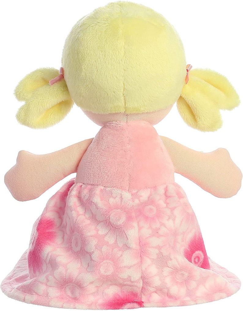 May include: A pink and white plush doll with blonde hair in pigtails. The doll is wearing a pink dress with a floral pattern.