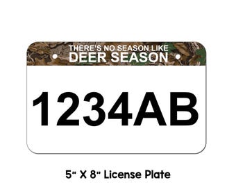May include: A white license plate with a camouflage pattern border. The text "There's no season like deer season" is printed on the border. The license plate number "1234AB" is printed in black on the white background. The license plate is 5 inches by 8 inches.