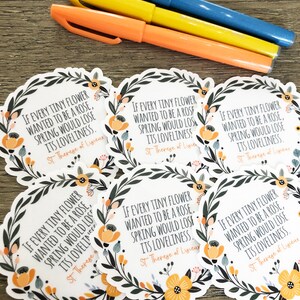 Op de afbeelding: Zes ronde stickers met een bloemige rand en een citaat van Heilige Theresia van Lisieux: "Als elke kleine bloem een roos wilde zijn, zou de lente zijn schoonheid verliezen."
