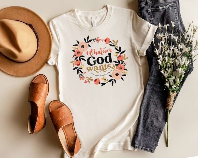 Puede incluir: Camiseta blanca con un dise&ntilde;o de corona floral y el texto "Whatever God Wants" en letras negras.