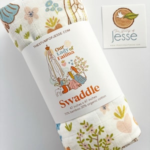 May include: A rolled-up white swaddle blanket with a floral pattern and the text "Our Lady of Fatima." The blanket is 47 inches by 47 inches and made of 70% bamboo and 30% organic cotton. A small card with a logo is next to the blanket.