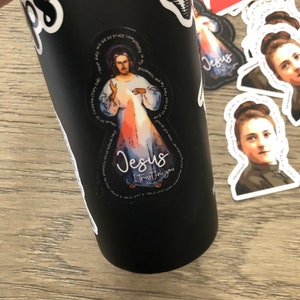 Może przedstawiać: Czarna butelka z wodą z naklejką Jezusa z napisem "Jezu, ufam Tobie" i cytatem św. Faustyny.