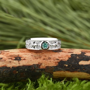 May include: A silver ring featuring an intricate Celtic design and a green gemstone at its centre.