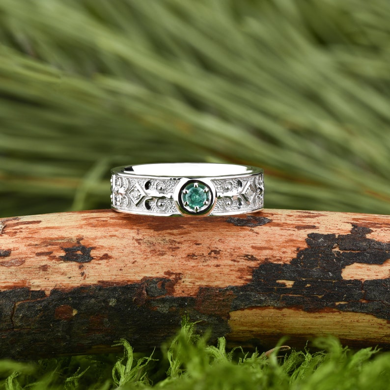 May include: A silver ring featuring an intricate Celtic design and a green gemstone at its centre.