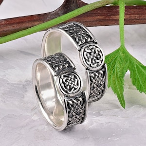 May include: Two silver rings with Celtic knot designs. The rings are interlocked and feature intricate knotwork patterns.