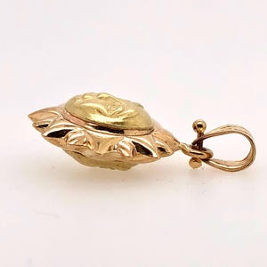 May include: A gold sun pendant with a detailed face design. The pendant has a loop for attaching to a chain.