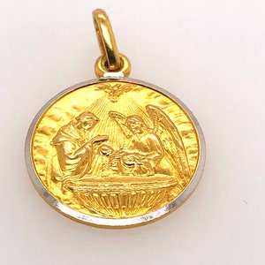 May include: A gold and silver pendant with a religious image of a baptism. The pendant features a figure of a priest baptizing a baby with a dove above them.