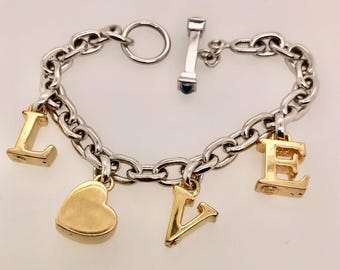 May include: A silver chain bracelet with a heart and letter charms spelling out "LOVE". The charms are gold colored.