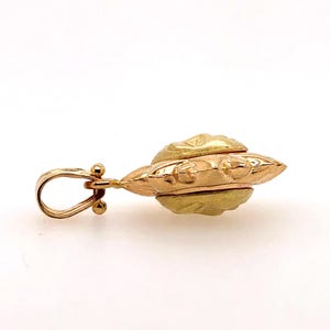 May include: A gold pendant with a detailed, ornate design. The pendant has a loop for attaching to a chain.