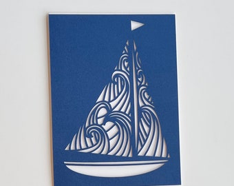 May include: A blue card with a white cutout of a sailboat with waves. The sailboat has a small flag at the top.