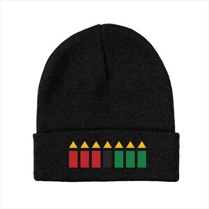 May include: Black beanie with a red, black, and green design on the cuff. The design features a row of yellow triangles above a row of red, black, and green rectangles.