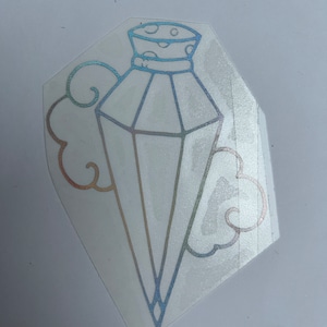 May include: A holographic sticker of a diamond-shaped bottle with a crown-like top and a cloud design around it.
