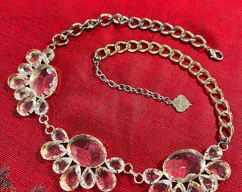 May include: A gold and silver chain necklace with a crystal pendant. The pendant is made up of several large, clear crystals that are connected together. The necklace is a statement piece that would be perfect for a special occasion.