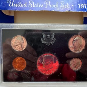 Könnte beinhalten: Ein 1972 United States Proof Set in einem transparenten Kunststoffetui. Das Set enthält fünf kupferfarbene Münzen und eine silberfarbene Münze. Auf der Oberseite des Etuis steht der Text "United States Proof Set 1972".