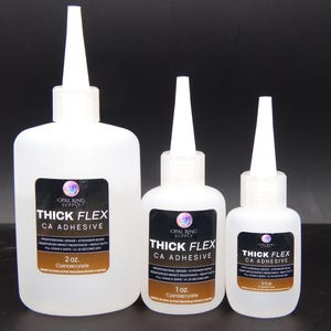 May include: Three white plastic bottles of Thick Flex CA Adhesive, with white applicator tips. The bottles are labeled with black and gold labels, and the sizes are 2 oz, 1 oz, and 0.5 oz.