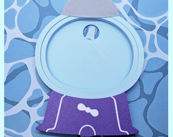 May include: A flat, die-cut gumball machine shape made of layered cardstock. The top globe is light blue with a silver glitter lid, while the base is purple with white line details and a small white bow graphic centered on the front.