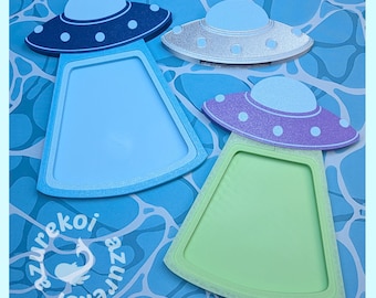 May include: Three UFO-shaped frames with glittery tops and solid-colored centers. One frame is dark blue with a light blue center, one is silver with a light blue center, and one is purple with a light green center. The text azurekoi is visible.