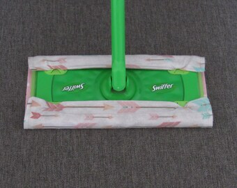 May include: A green Swiffer wet jet mop with a white and pink patterned cleaning pad. The pad has a design of pink arrows on a white background.