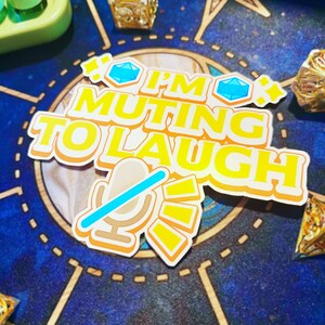 Pu&ograve; includere: Un adesivo giallo e arancione con il testo "I'm muting to laugh" e un'icona di microfono con una linea blu che lo attraversa.