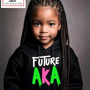 May include: A young girl wearing a black hooded sweatshirt with the words "FUTURE AKA" in white, green, and pink. The image includes the logo for "TWO BLACK TEES" in a white box with black text.