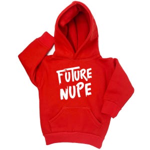 May include: A bright red hooded sweatshirt with the text "FUTURE NUPE" in white, bold, brush-style lettering. The sweatshirt has a kangaroo pocket and ribbed cuffs and hem. The hood is up, and the sleeves are extended.