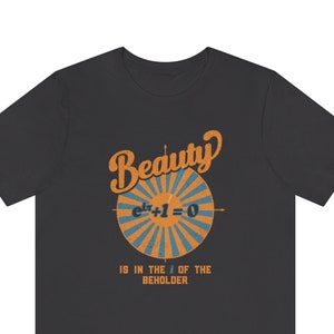 Może przedstawiać: Szary t-shirt z nadrukiem koła z pomarańczowymi i niebieskimi paskami i równaniem "e^ix + 1 = 0" w środku. Pod kołem znajduje się napis "Piękno tkwi w oku patrzącego".
