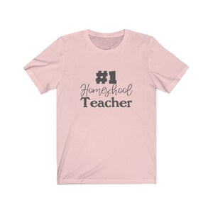 K&ouml;nnte beinhalten: Ein rosa T-Shirt mit dem Text "#1 Homeschool Teacher" in Schwarz.